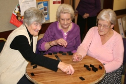 Enjoying their game of dominoes at the Open Door Club are, from left, Jean Morgan, June Adams and Isa Johnston.